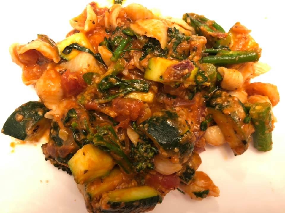 Vegetarian pasta with sauce going over all the vegetables and fluffy pasta
